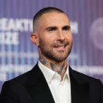 Adam Levine posing for the cameras in an elegant suit