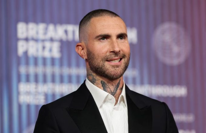 Adam Levine posing for the cameras in an elegant suit
