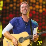 The famous British singer holding a guitar in the middle of a concert