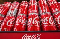 Many Coca-Cola cans stacked on top of each other on a supermarket display stand