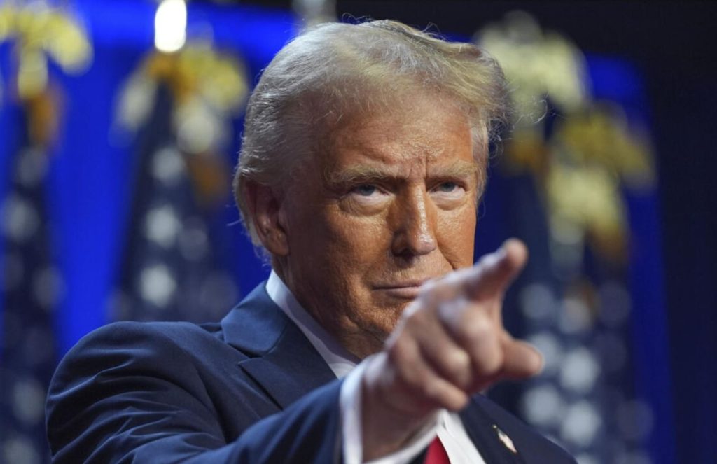 The President of the United States pointing forward with his finger while maintaining a serious expression