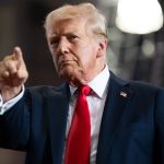 Donald Trump wearing an elegant suit, pointing forward with a very serious expression on his face