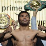 The Thai boxer posing with his fists in the air during a presentation in front of a large crowd