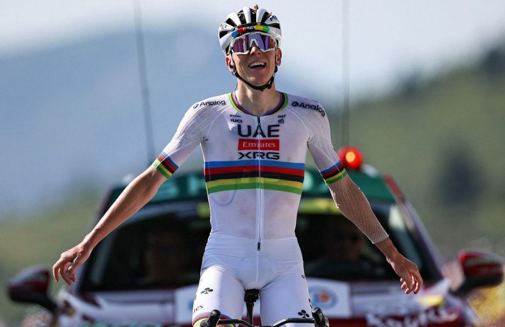 The great Slovenian cyclist riding his bike, wearing a white outfit with colored stripes around the abdomen area