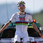 The great Slovenian cyclist riding his bike, wearing a white outfit with colored stripes around the abdomen area