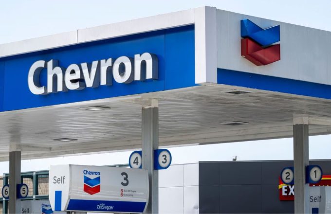 A gas station with the word "Chevron" in white letters against a sky-blue background