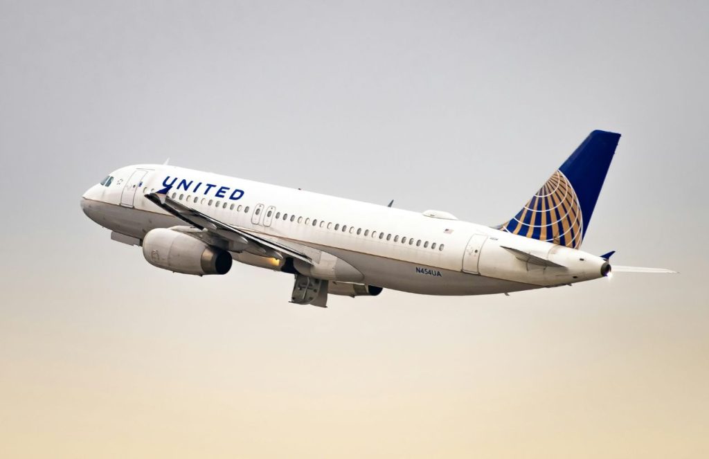 A large United Airlines plane soaring through the vast blue sky