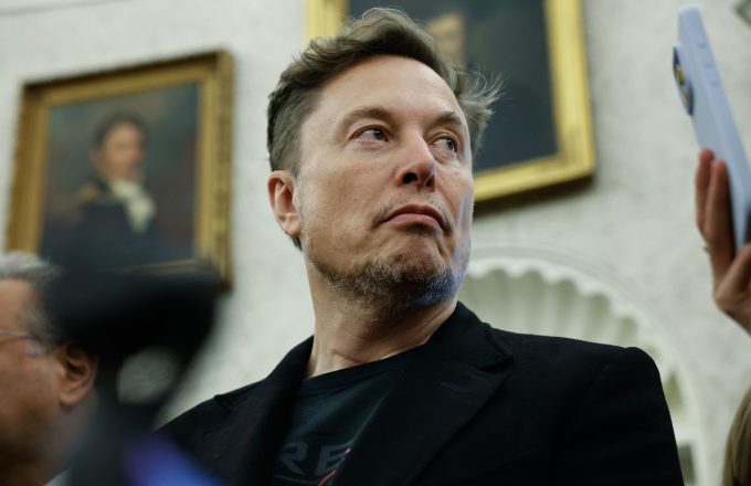 Elon wearing an elegant black suit and looking to the side
