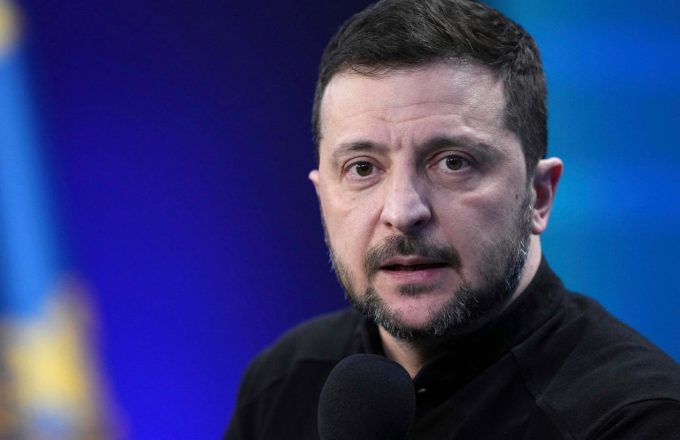 The Ukrainian president with long hair and a beard, staring intently at the audience while giving a speech