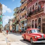 The old and desolate streets of Havana, Cuba, with a red car parked