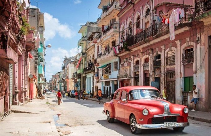 The old and desolate streets of Havana, Cuba, with a red car parked