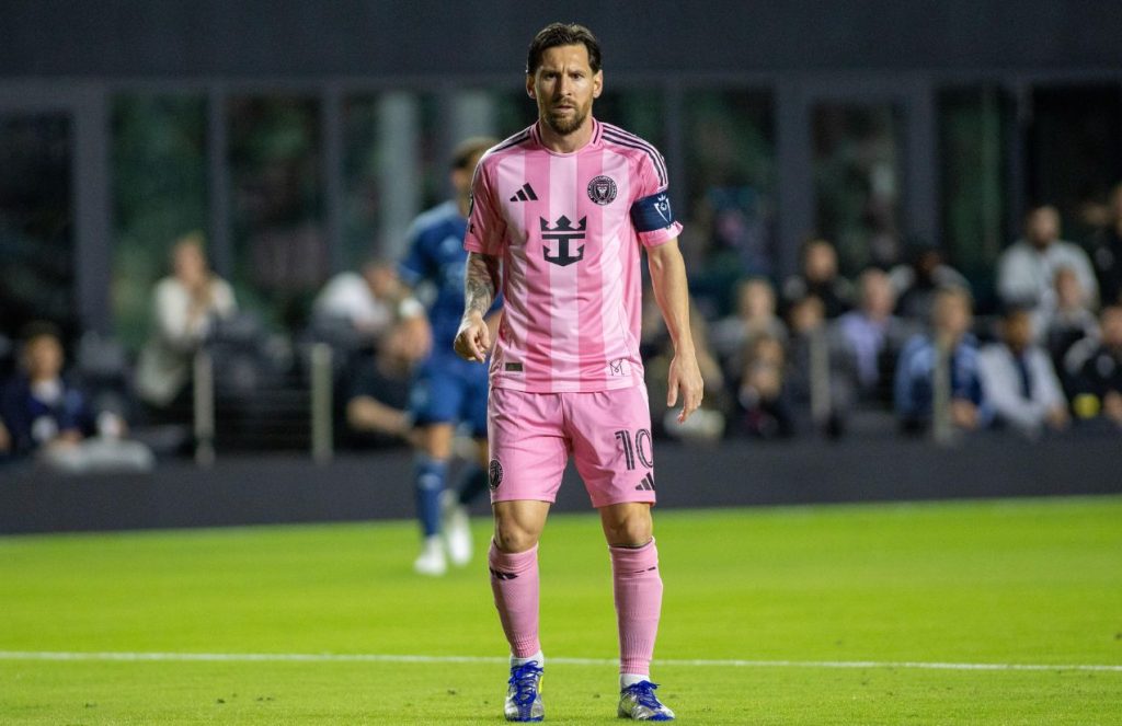 Messi on the field wearing Inter Miami’s pink uniform, about to strike the ball