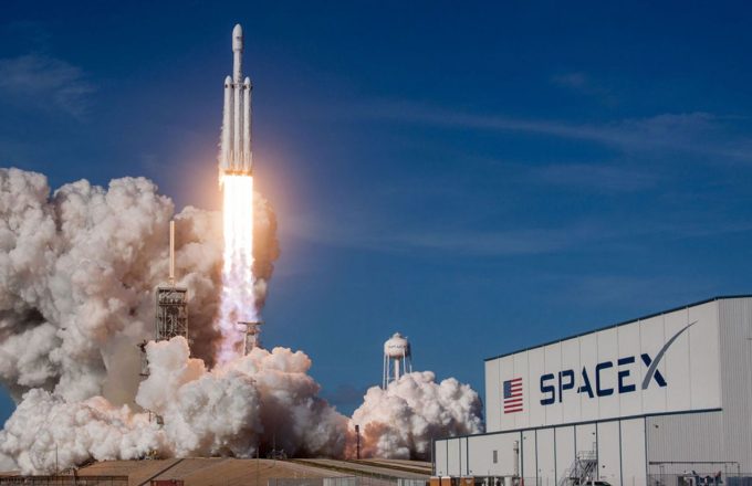 A rocket releasing thick smoke as it launches into the vast blue sky