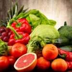 Several fruits and vegetables arranged on a kitchen counter on top of a table