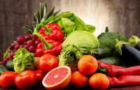 Several fruits and vegetables arranged on a kitchen counter on top of a table