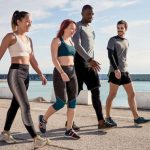 Four people walking outdoors wearing tight-fitting workout clothes