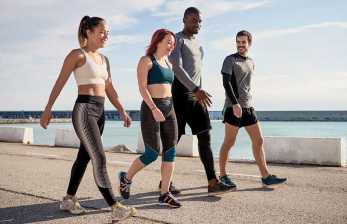 Four people walking outdoors wearing tight-fitting workout clothes