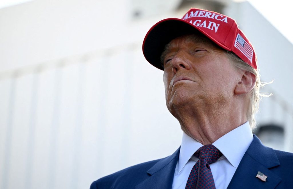 Donald Trump wearing a formal suit complemented by a red cap with the words "Make America Great Again."