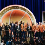 NBA players posing on the Hall of Fame stage holding their trophies and golden jackets