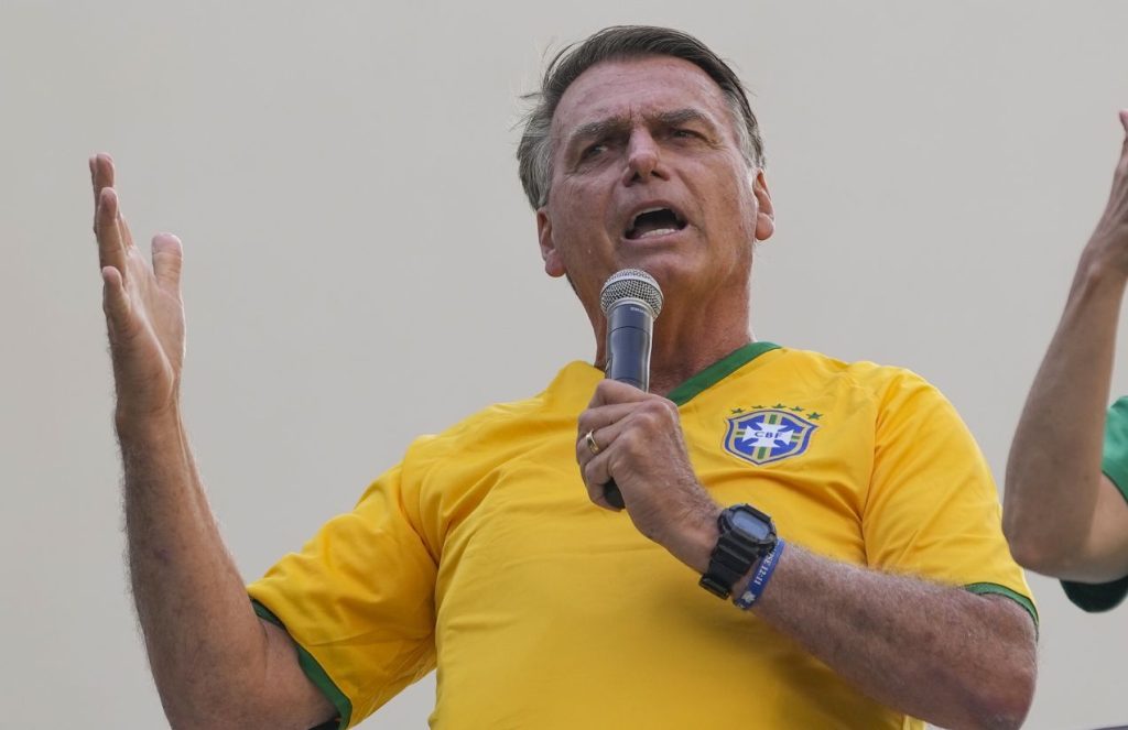Brazil on edge as Bolsonaro faces historic trial for alleged coup attempt Bolsonaro wearing the Brazil jersey and holding a microphone while speaking to the crowd