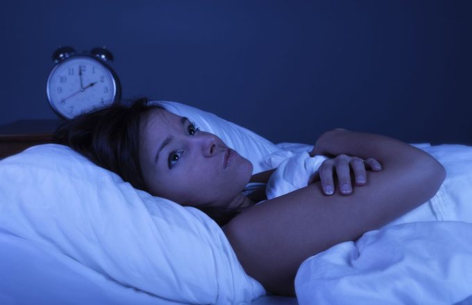 An angry woman lying in bed unable to sleep