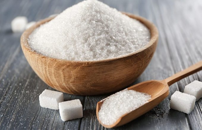 A bowl of sugar on a table next to several small sugar cubes