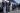 Several people being detained, lined up against a wall for a search