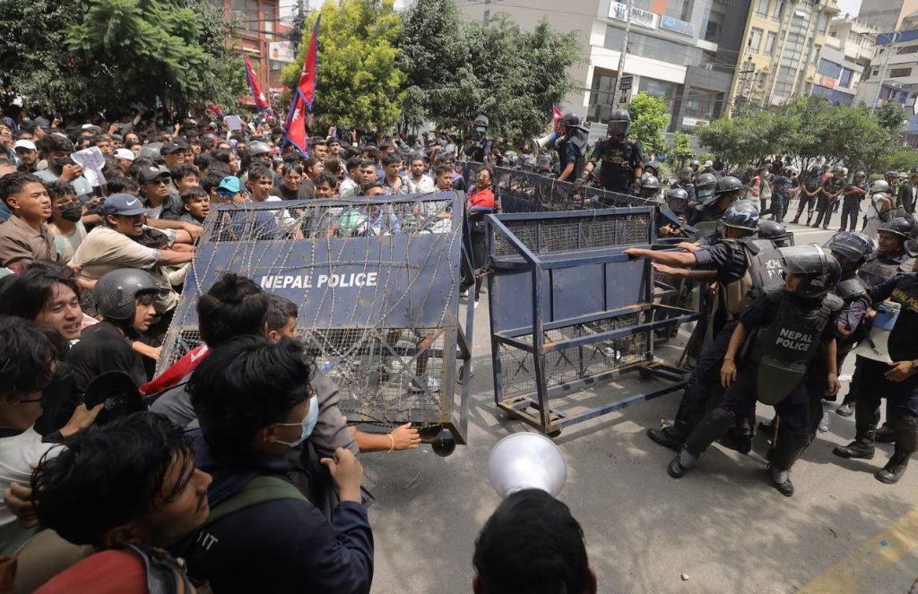 Young people in Nepal confronting the country’s police while breaking through a security barrier