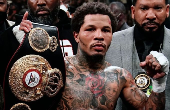 The famous American boxer raising one hand in celebration while holding up the championship belt with the other