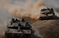 Two war tanks speeding through the vast Middle Eastern desert