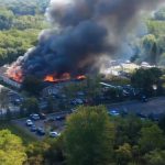 A church engulfed in flames with many police cars around it watching the scene