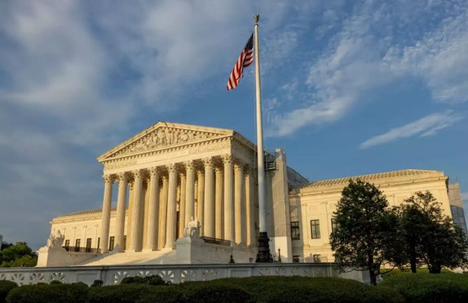 The building of the United States Supreme Court in its striking and imposing white color, with a flag of the same country at its entrance