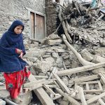 A woman walking over the rubble of a building in Afghanistan