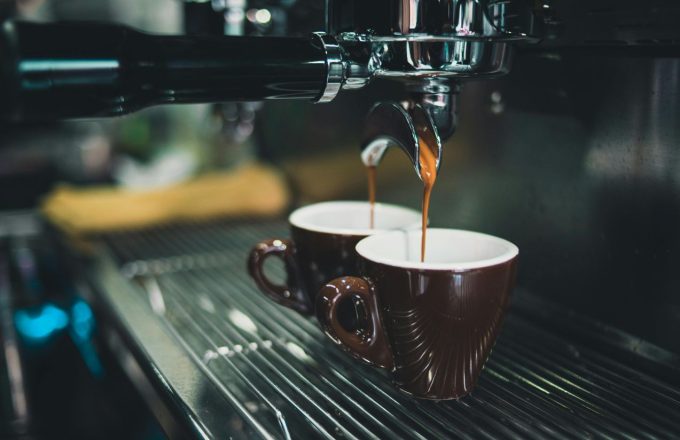 A coffee vending machine filling two cups with the precious liquid