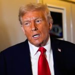 Donald Trump giving a conference in front of the cameras wearing a beautiful black suit