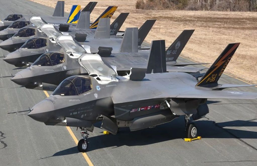 Several F-35s lined up in a row on an airfield