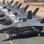 Several F-35s lined up in a row on an airfield