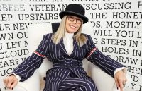 A silent goodbye: Diane Keaton’s death linked to pneumonia The iconic actress sitting on a couch wearing a black and white striped suit while smiling happily