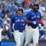 Three Blue Jays players celebrating after scoring multiple runs against the Yankees