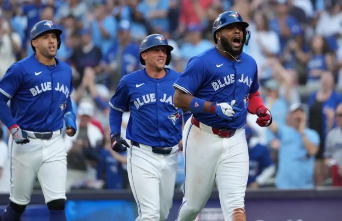 Three Blue Jays players celebrating after scoring multiple runs against the Yankees
