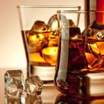 Two glasses filled with liquor and ice on a table