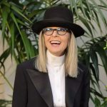 The iconic actress smiling at the camera while wearing a striking black-and-white outfit and a large hat