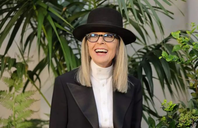 The iconic actress smiling at the camera while wearing a striking black-and-white outfit and a large hat