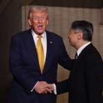 Trump holding hands with the Japanese prime minister as both smile happily
