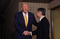 Trump holding hands with the Japanese prime minister as both smile happily