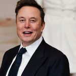 Elon Musk wearing an elegant black suit while posing for the cameras