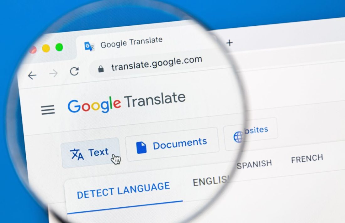 The Google Translate webpage open on a computer screen, with a person holding a magnifying glass to get a closer look at the page’s name