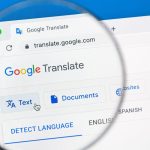 The Google Translate webpage open on a computer screen, with a person holding a magnifying glass to get a closer look at the page’s name