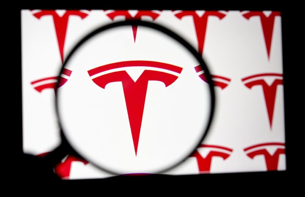 The Tesla logo seen through a magnifying glass for a closer look