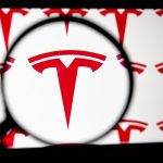 The Tesla logo seen through a magnifying glass for a closer look